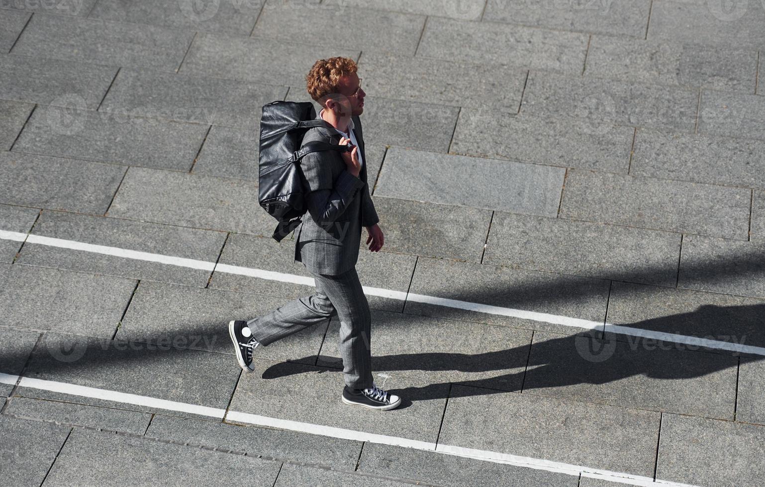 promenader på de väg. ung affärsman i grå formell ha på sig är utomhus i de stad foto