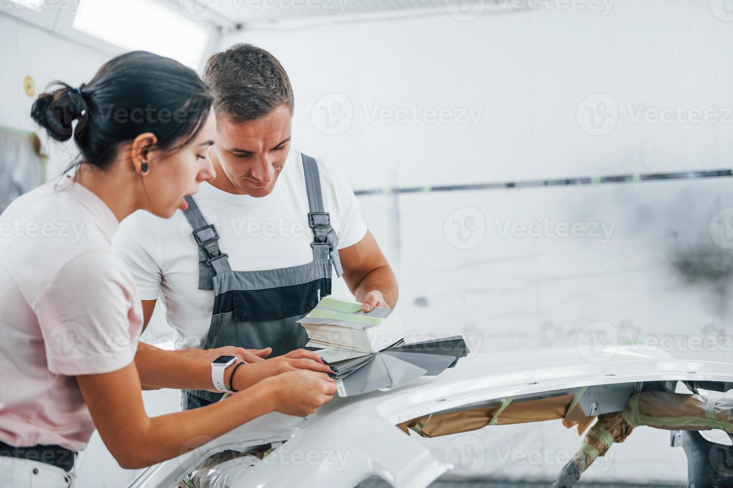 ung kvinna med man Arbetar tillsammans i bil reparera garage foto