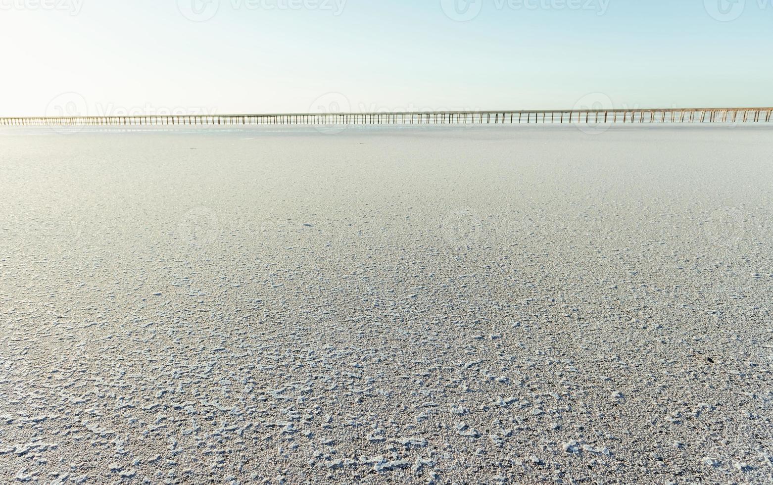 vit sand på de kust. bro är långt bort på bakgrund foto