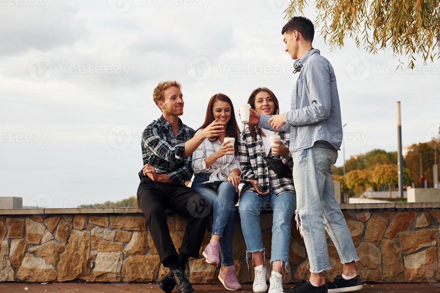 kaffe tid. grupp av ung glad vänner den där är utomhus har roligt tillsammans foto