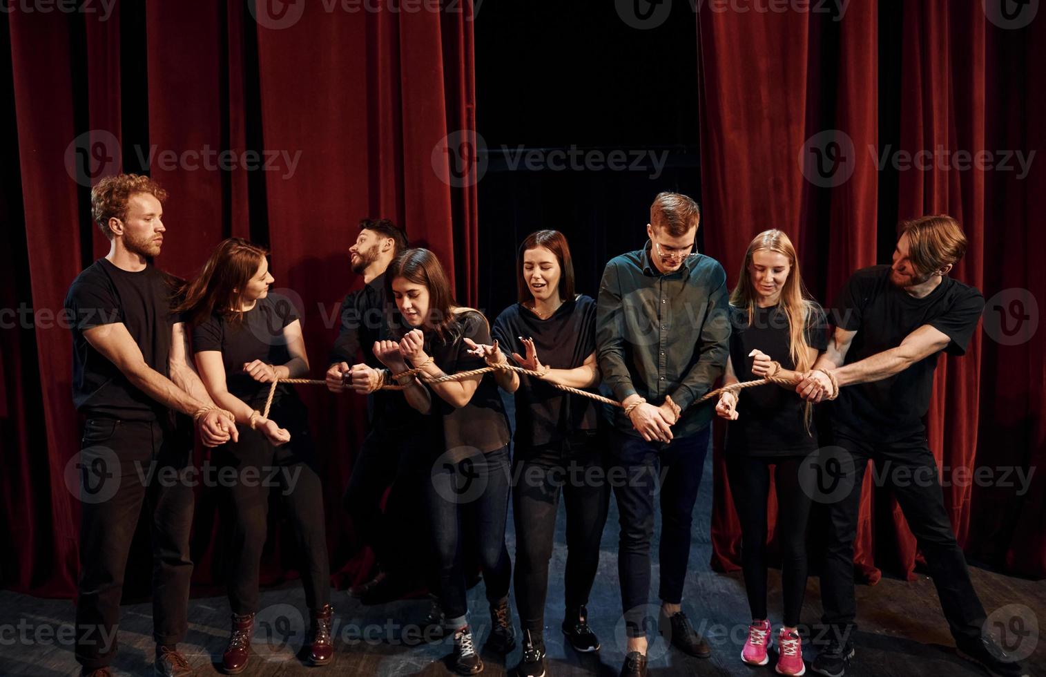 med rep i händer. grupp av aktörer i mörk färgad kläder på repetition i de teater foto