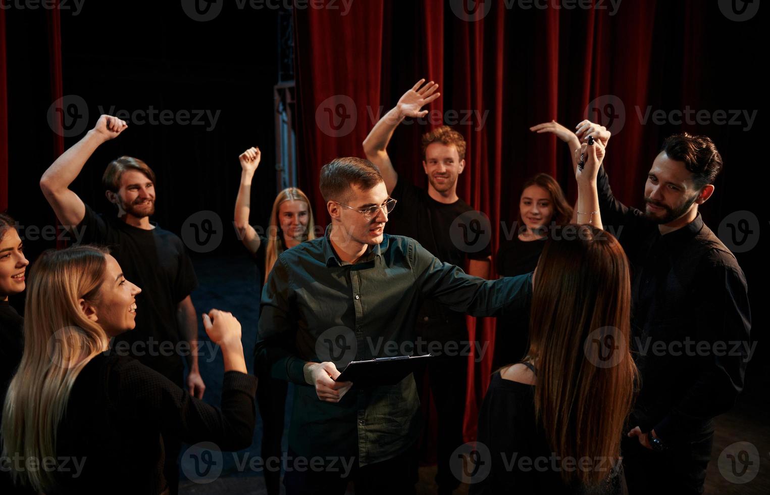 Lycklig människor fira Framgång. grupp av aktörer i mörk färgad kläder på repetition i de teater foto