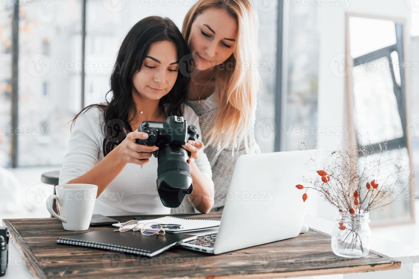 med bärbar dator och kamera. två ung kvinna frilansare arbetssätt inomhus i de kontor på dagtid foto