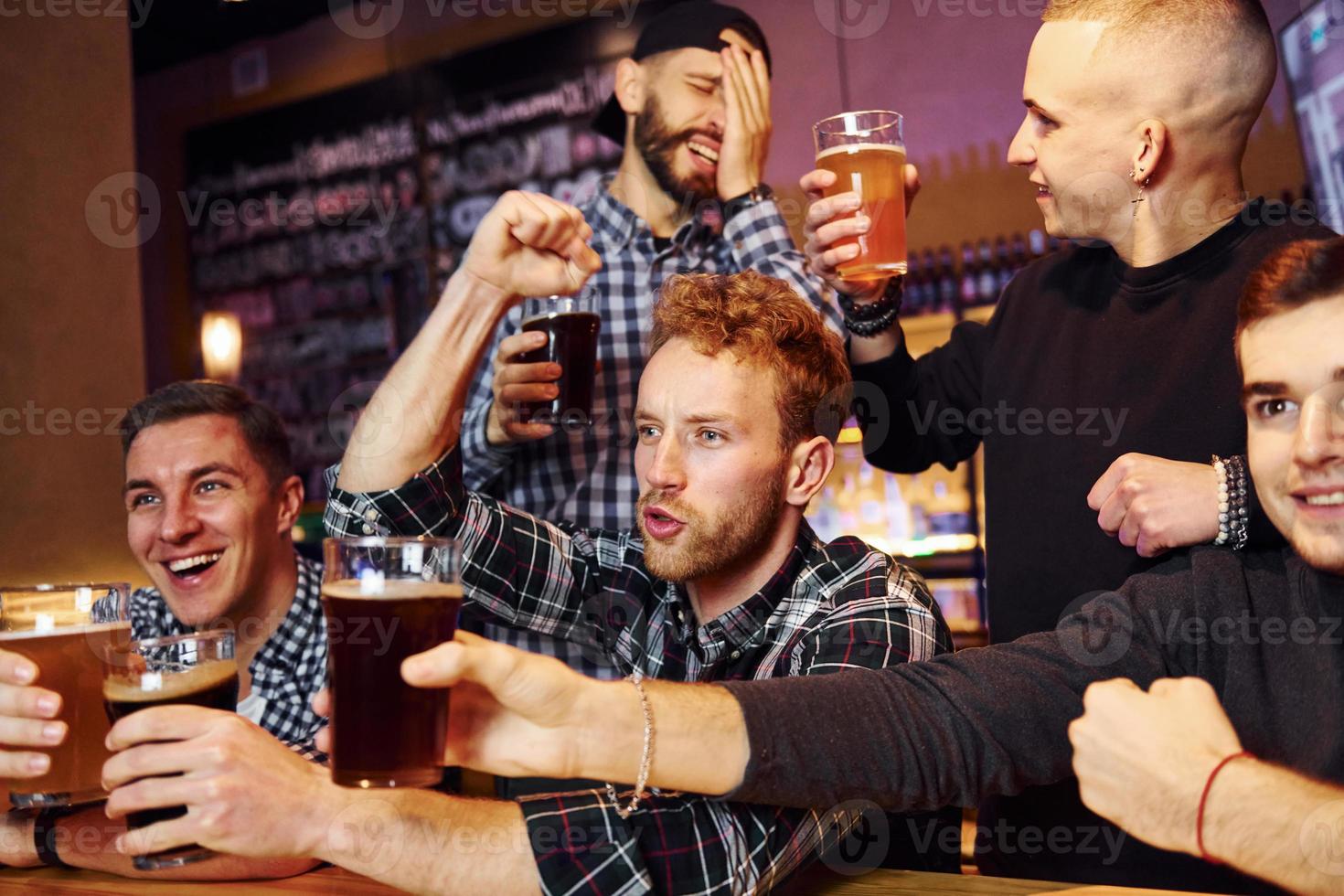 fotboll fläktar fira seger. grupp av människor tillsammans inomhus i de pub ha roligt på helgen tid foto