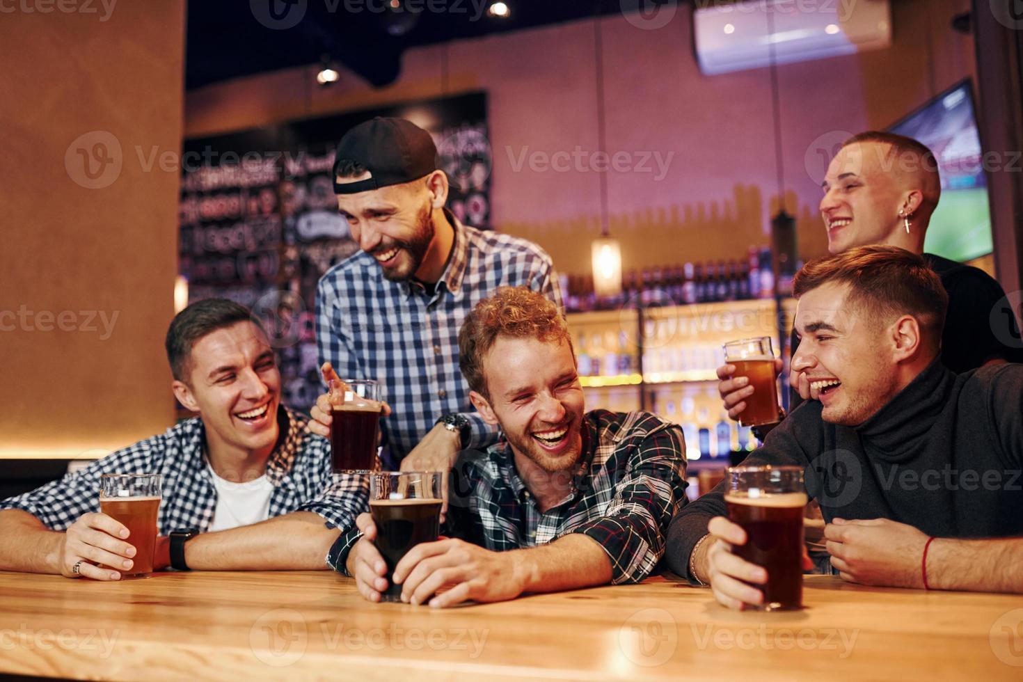 fotboll fläktar tittar på tv. grupp av människor tillsammans inomhus i de pub ha roligt på helgen tid foto