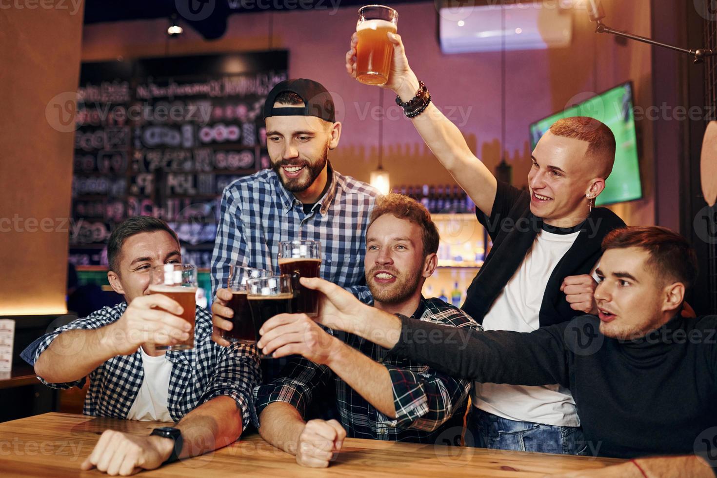 fotboll fläktar tittar på tv. grupp av människor tillsammans inomhus i de pub ha roligt på helgen tid foto