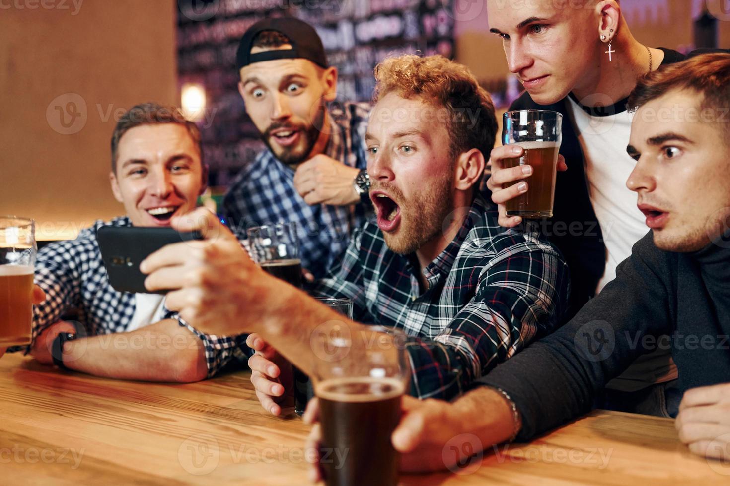 användningar telefon. grupp av människor tillsammans inomhus i de pub ha roligt på helgen tid foto