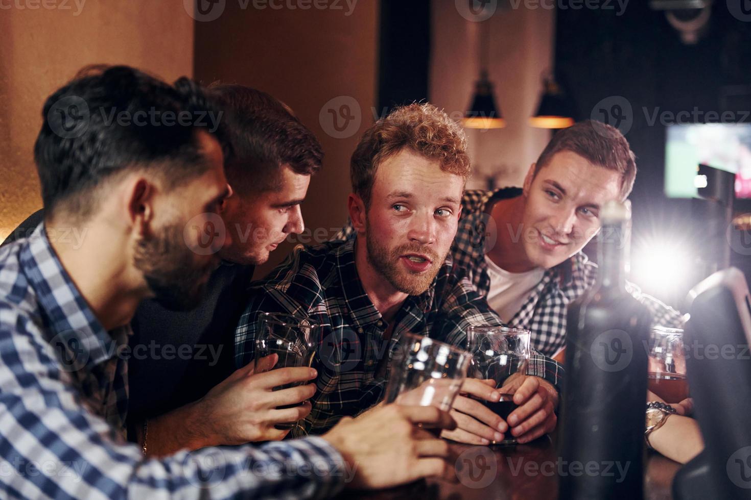 glädjande förbi knackar öl glasögon. grupp av människor tillsammans inomhus i de pub ha roligt på helgen tid foto