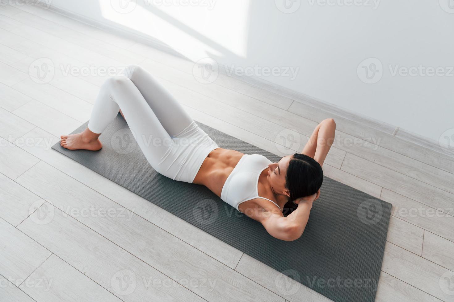 håller på med övningar. ung caucasian kvinna med smal kropp form är inomhus på dagtid foto