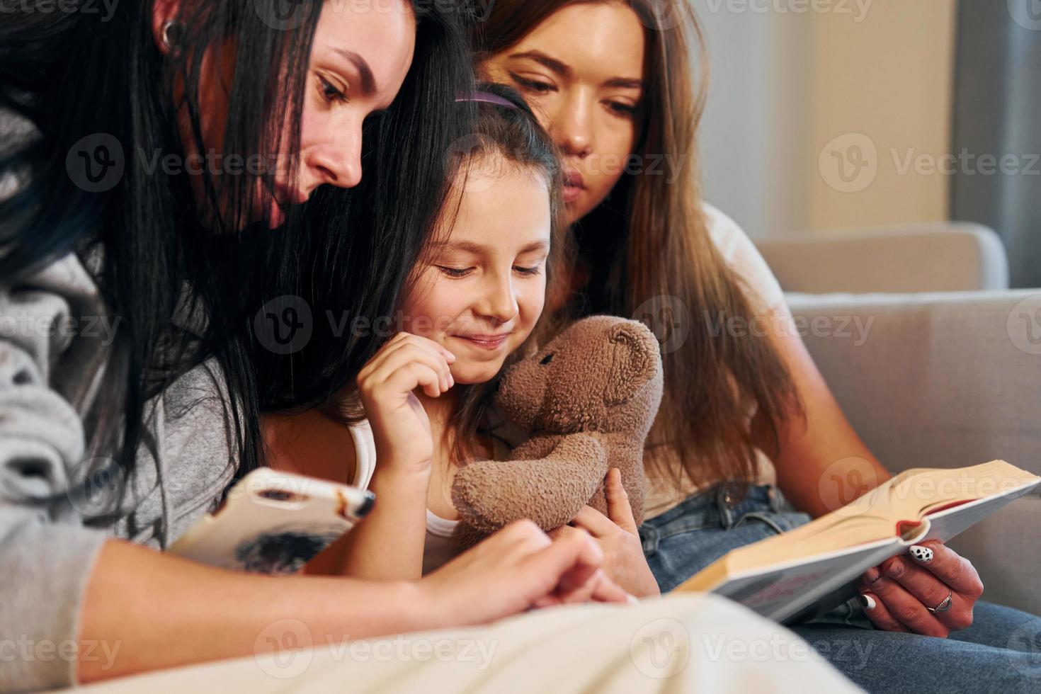 läsning bok tillsammans. kvinna lesbisk par med liten dotter utgifterna tid tillsammans på Hem foto