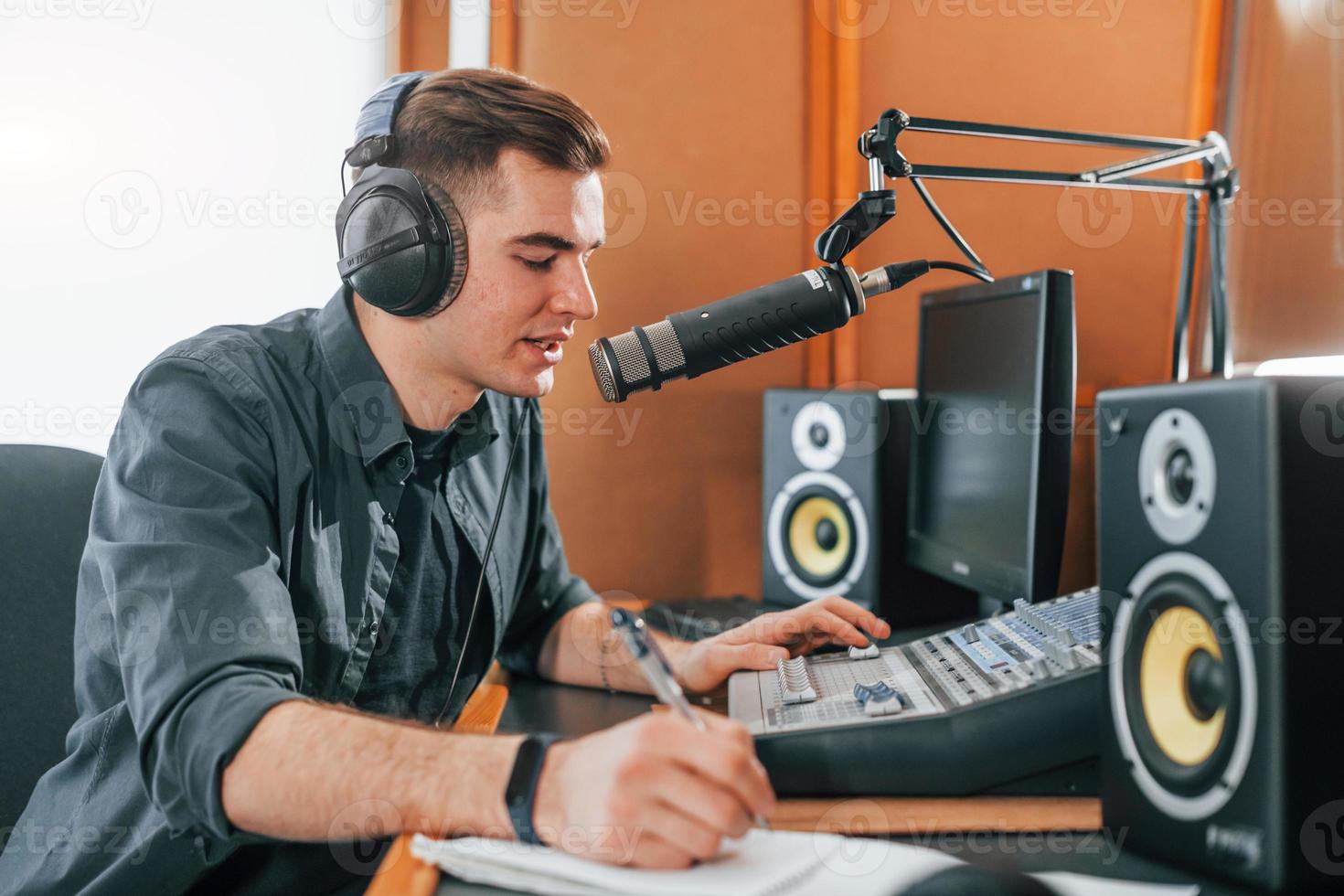 samtal och användningar mikrofon. ung man är inomhus i de radio studio är upptagen förbi utsända foto
