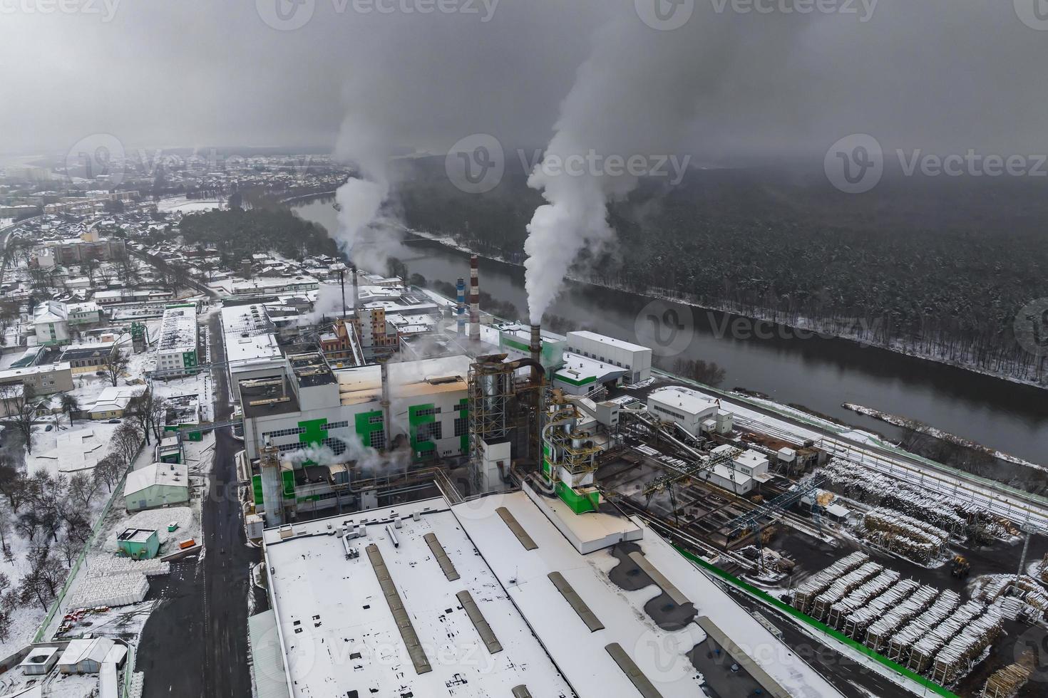 vinter- panorama- antenn se av mörk rök av rör av träbearbetning företag med snö. luft och vatten förorening begrepp. foto