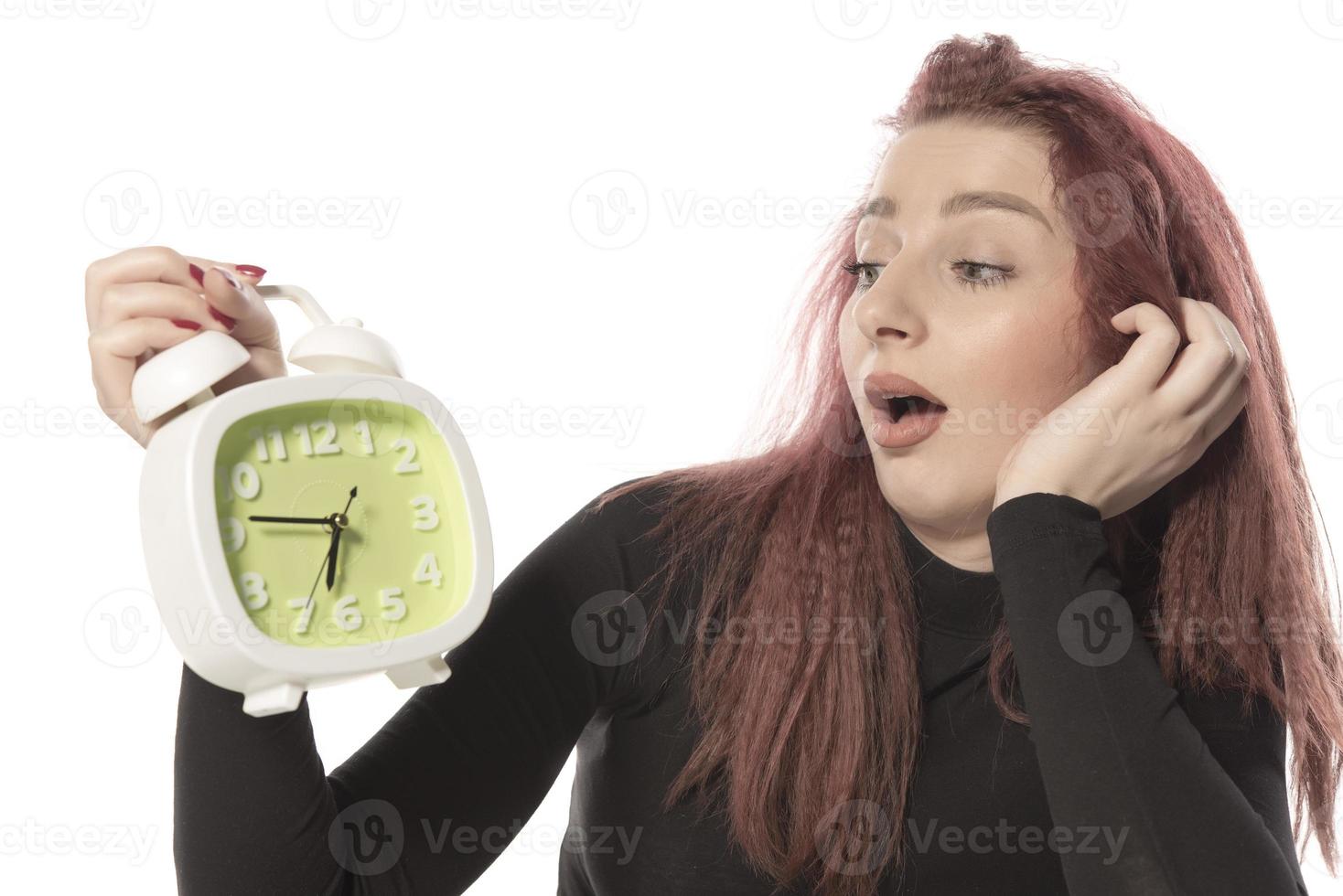 orolig ung kvinna innehav larm klocka i henne hand foto