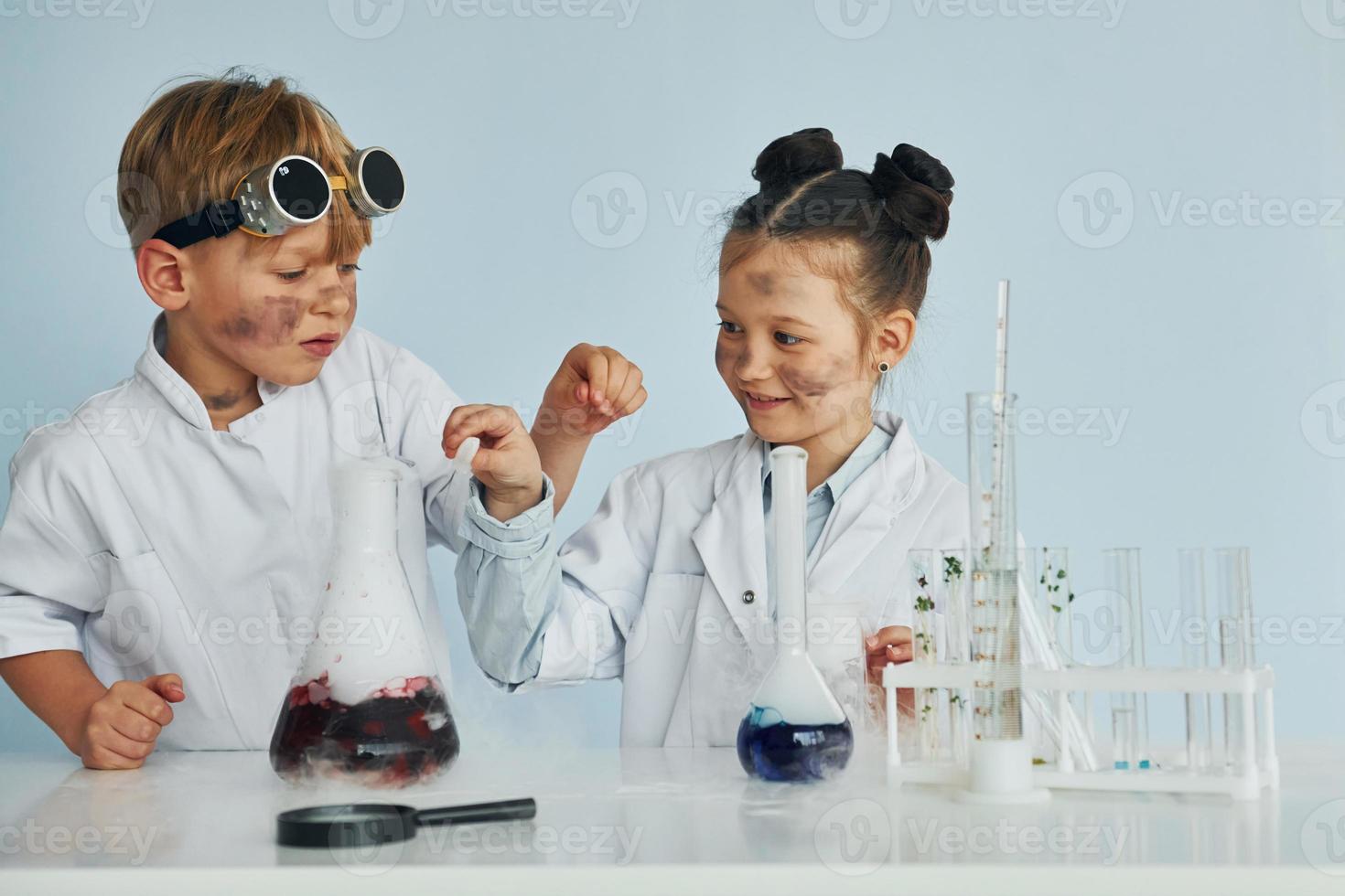 pojke Arbetar med flytande i testa rör. barn i vit rockar spelar en vetenskapsmän i labb förbi använder sig av Utrustning foto