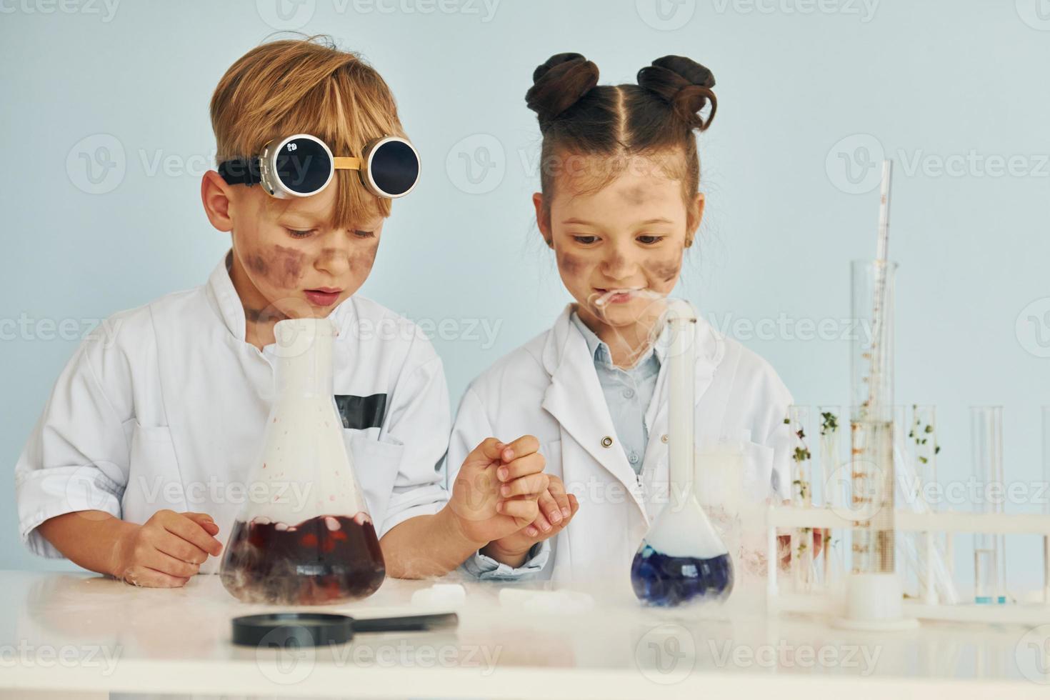 pojke Arbetar med flytande i testa rör. barn i vit rockar spelar en vetenskapsmän i labb förbi använder sig av Utrustning foto