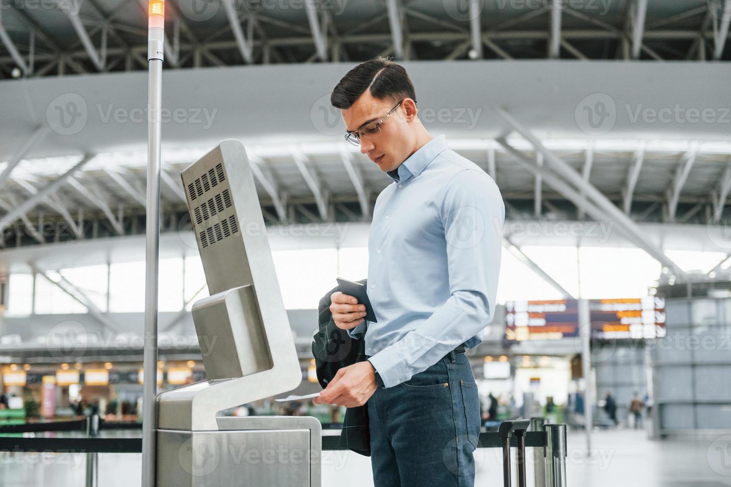 använder sig av terminal. ung affärsman i formell kläder är i de flygplats på dagtid foto