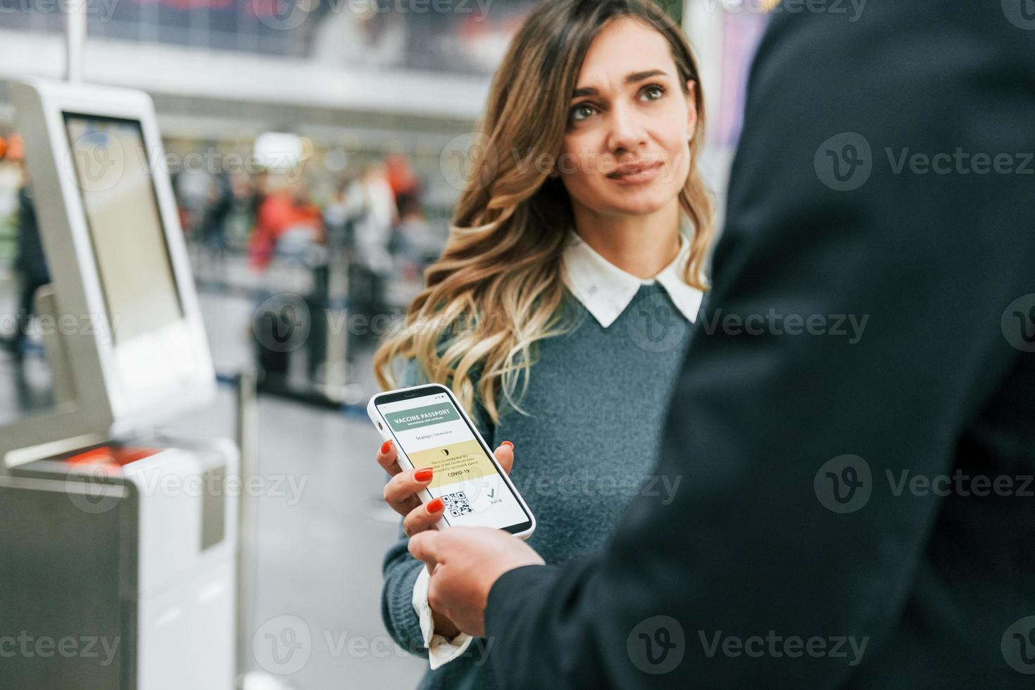certifikat av vaccination i de telefon. ung kvinna turist är i de flygplats på dagtid foto