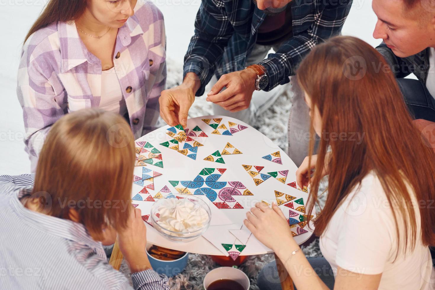 spelar pussel spel. grupp av vänner ha fest inomhus tillsammans foto