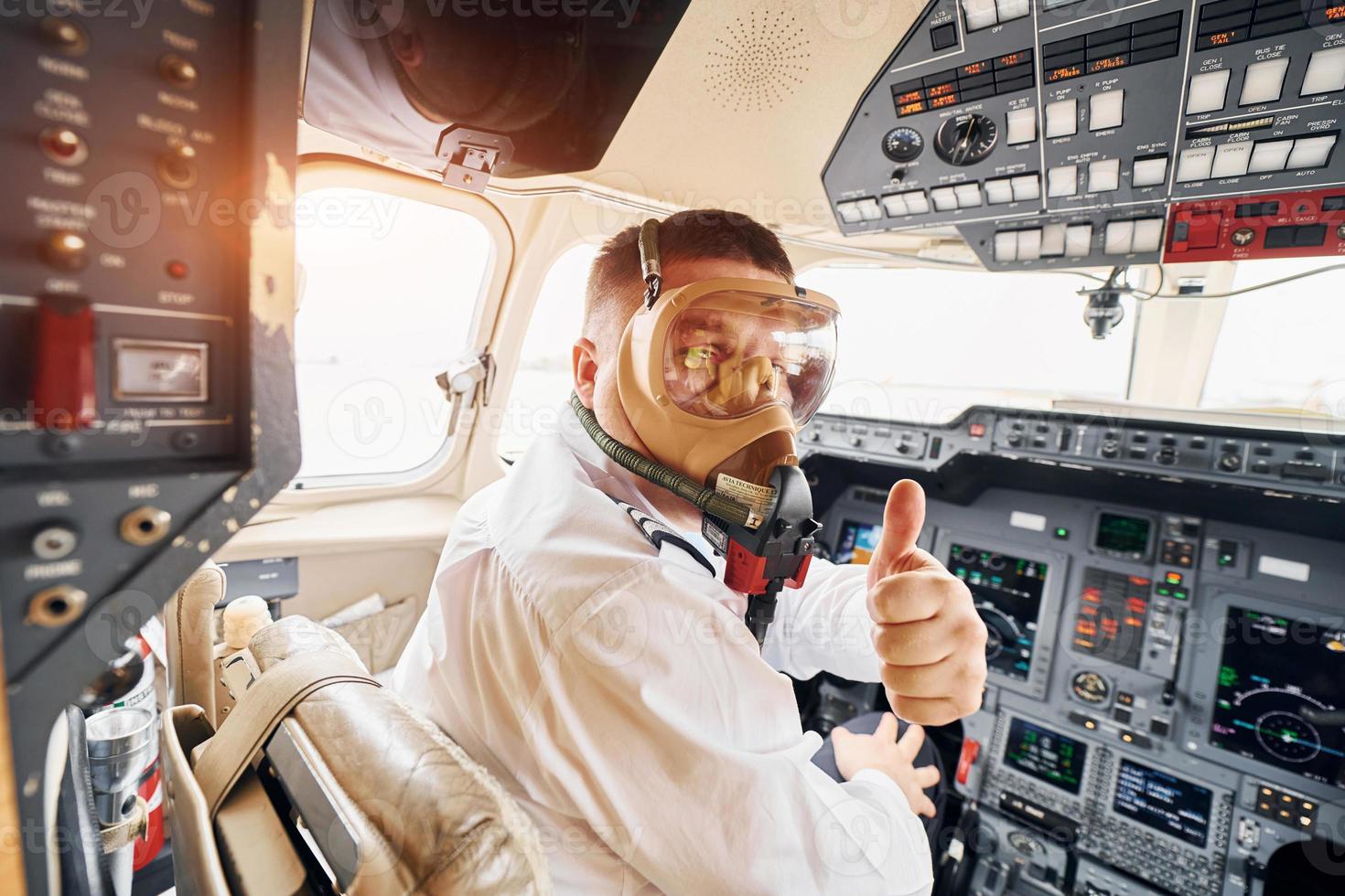 i syre mask. pilot i formell ha på sig sitter i de cockpit och kontroller flygplan foto