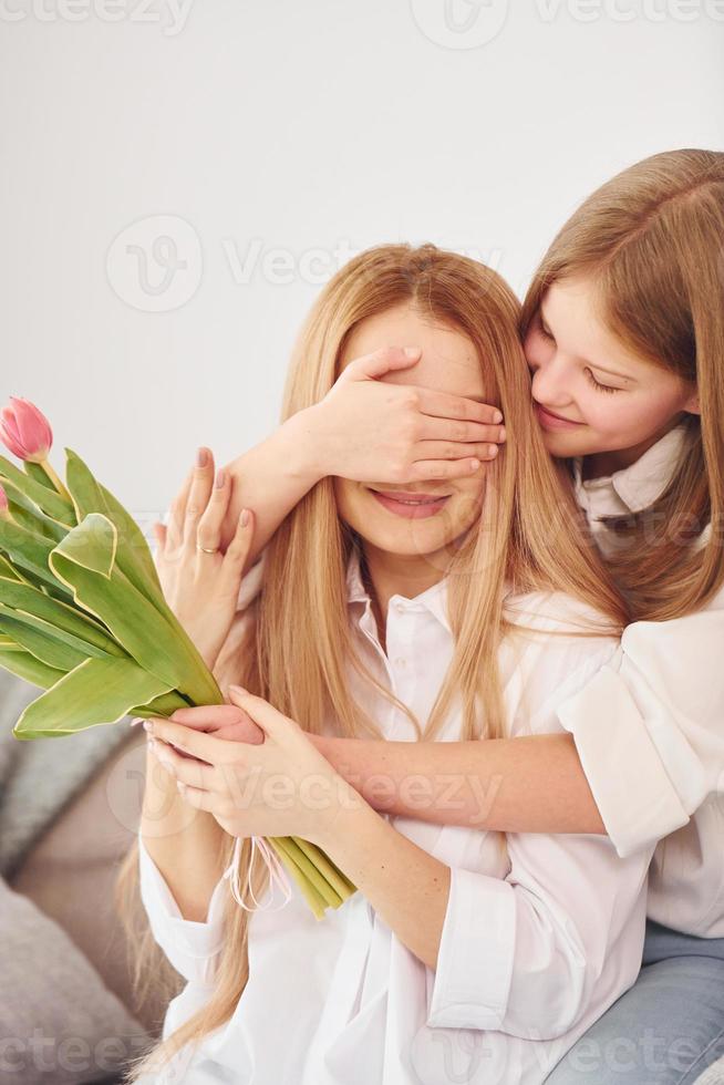 flickor ger blommor. ung kvinna med henne dotter är på Hem på dagtid foto