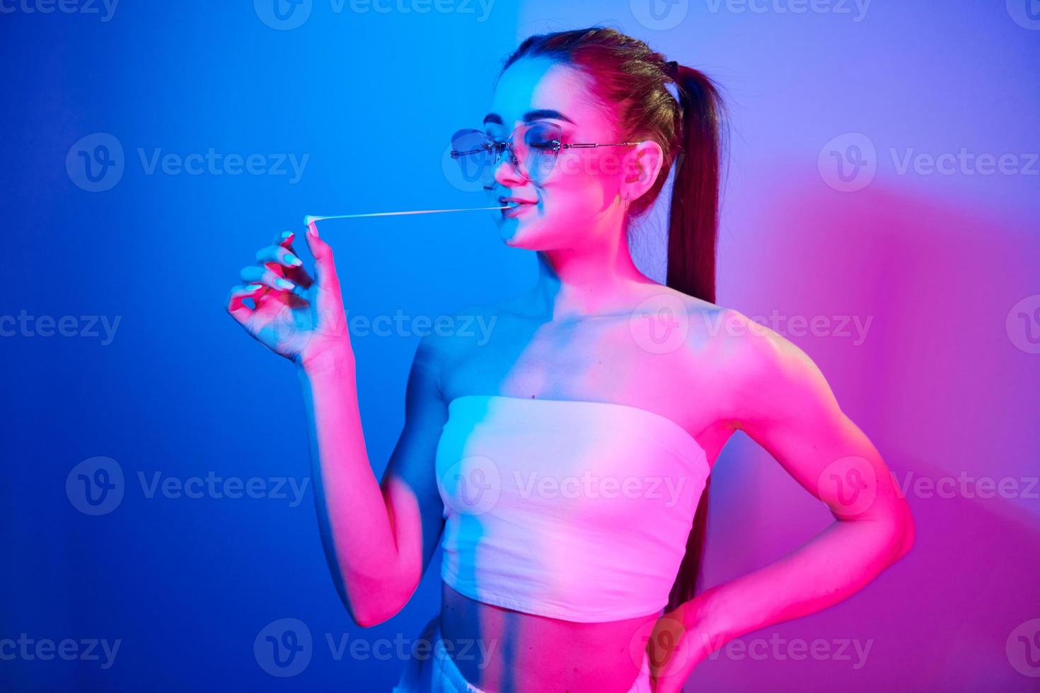 positiv känslor. modern ung kvinna stående i de studio med neon ljus foto