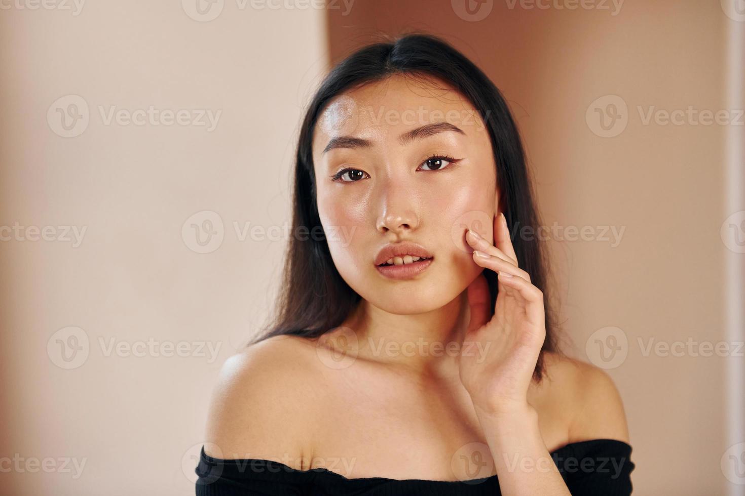 porträtt av ung allvarlig asiatisk kvinna den där stående inomhus foto
