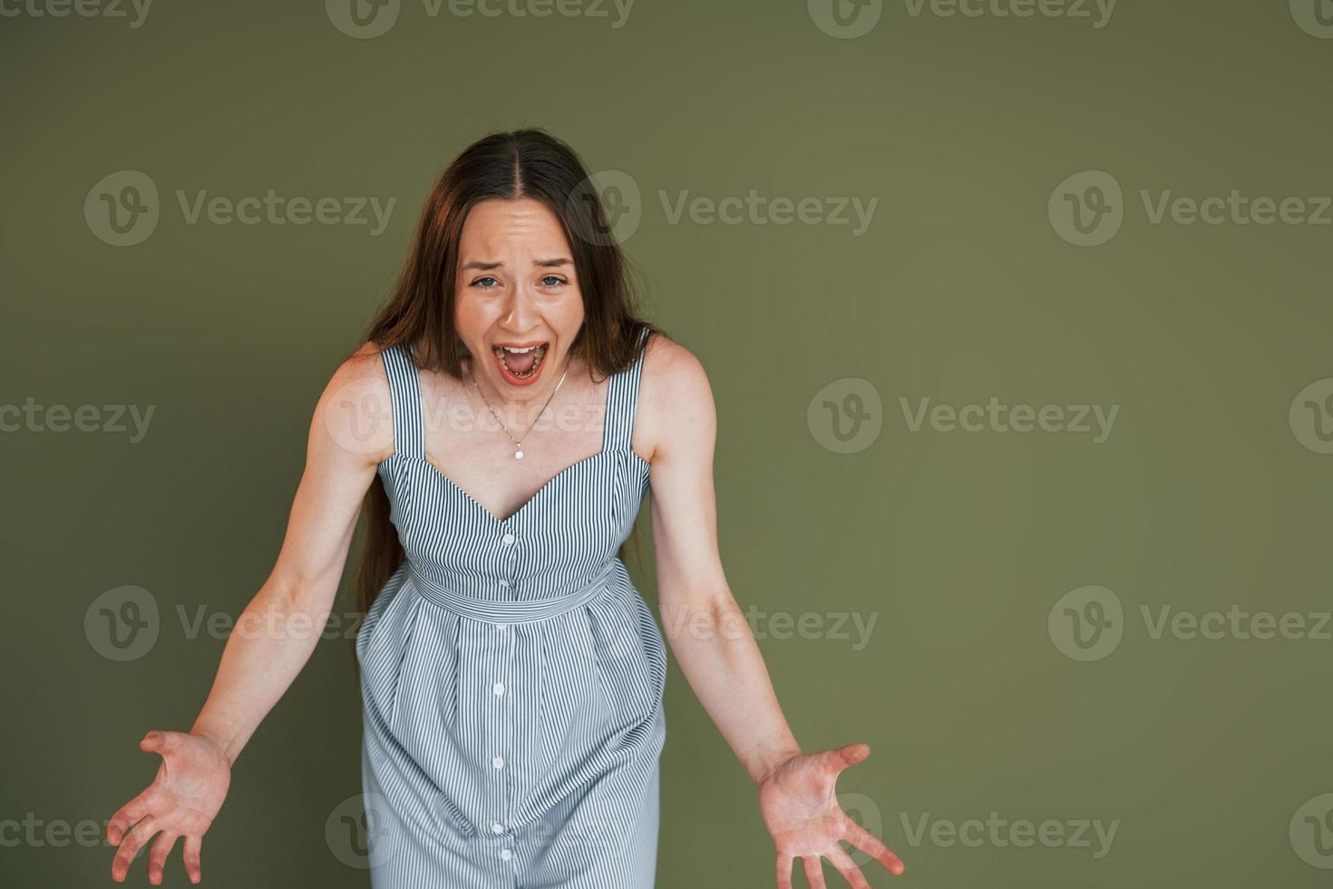 emotionell ung kvinna i tillfällig kläder stående inomhus i de studio foto