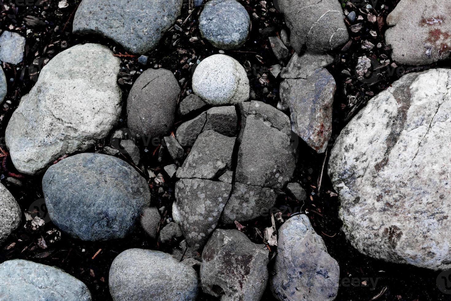 runda flod stenar och en knäckt sten bakgrund foto