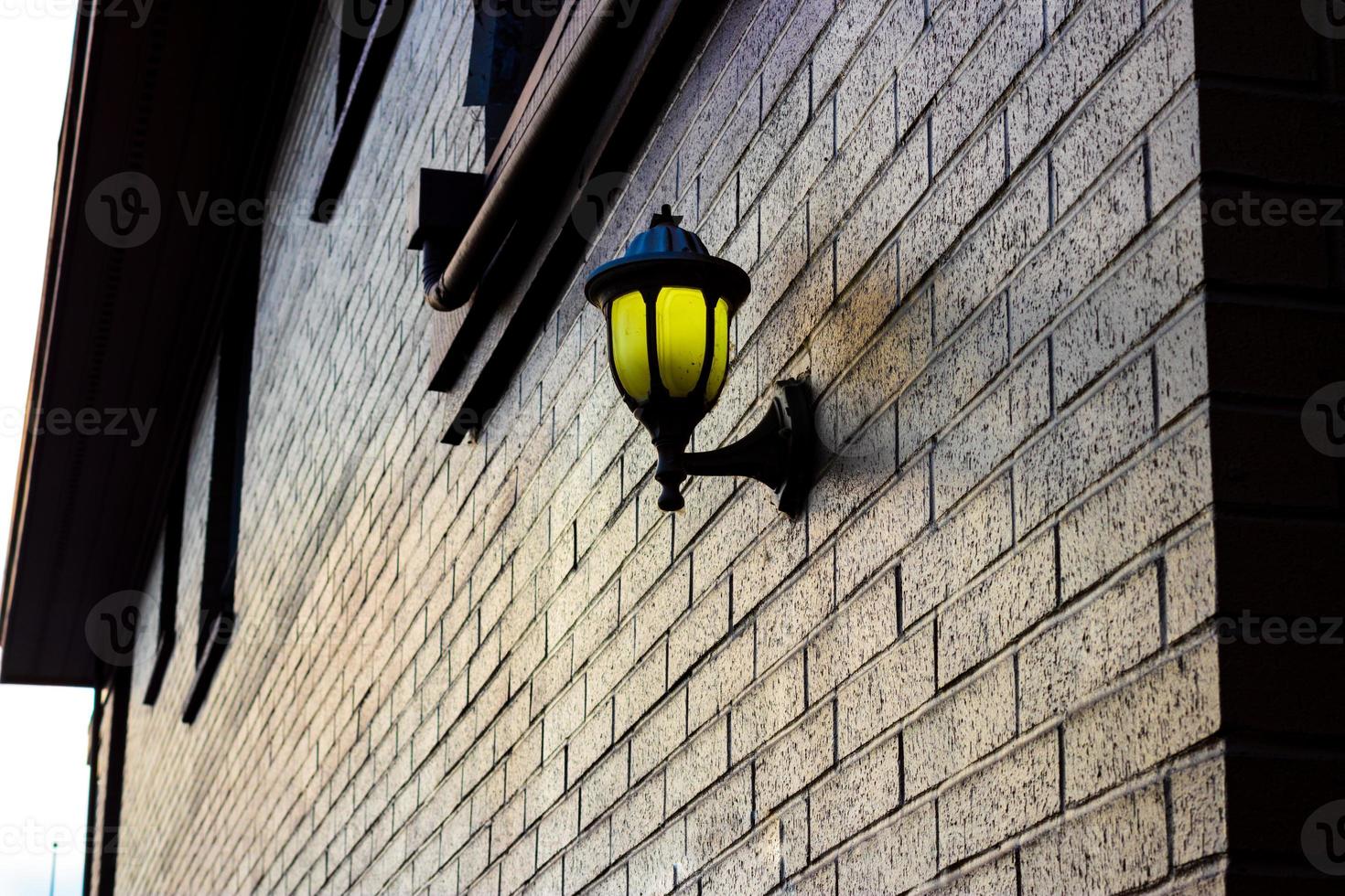 lampa monterad på en tegel vägg belysande gyllene ljus foto