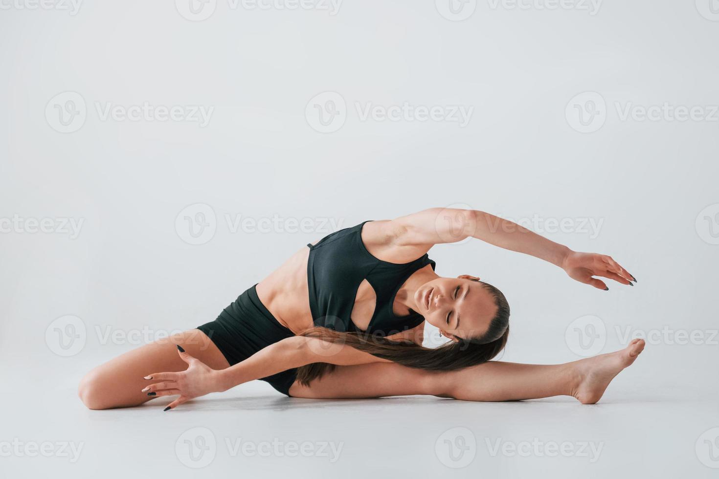 fokuserade på de övningar. ung kvinna i sportigt kläder håller på med gymnastik inomhus foto