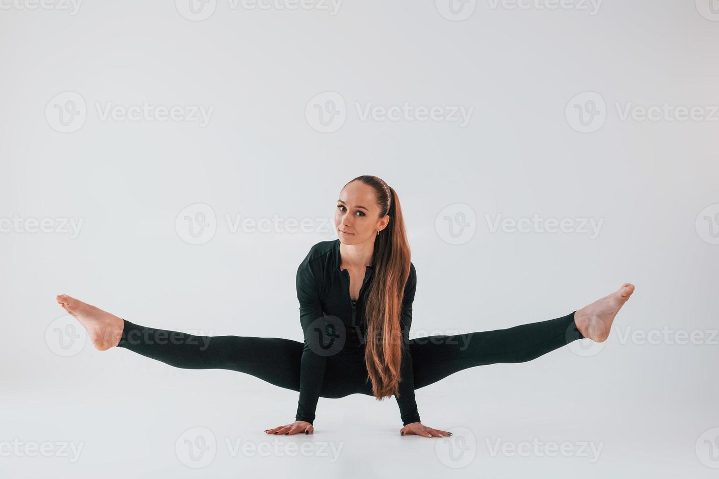 i svart kläder. ung kvinna i sportigt kläder håller på med gymnastik inomhus foto