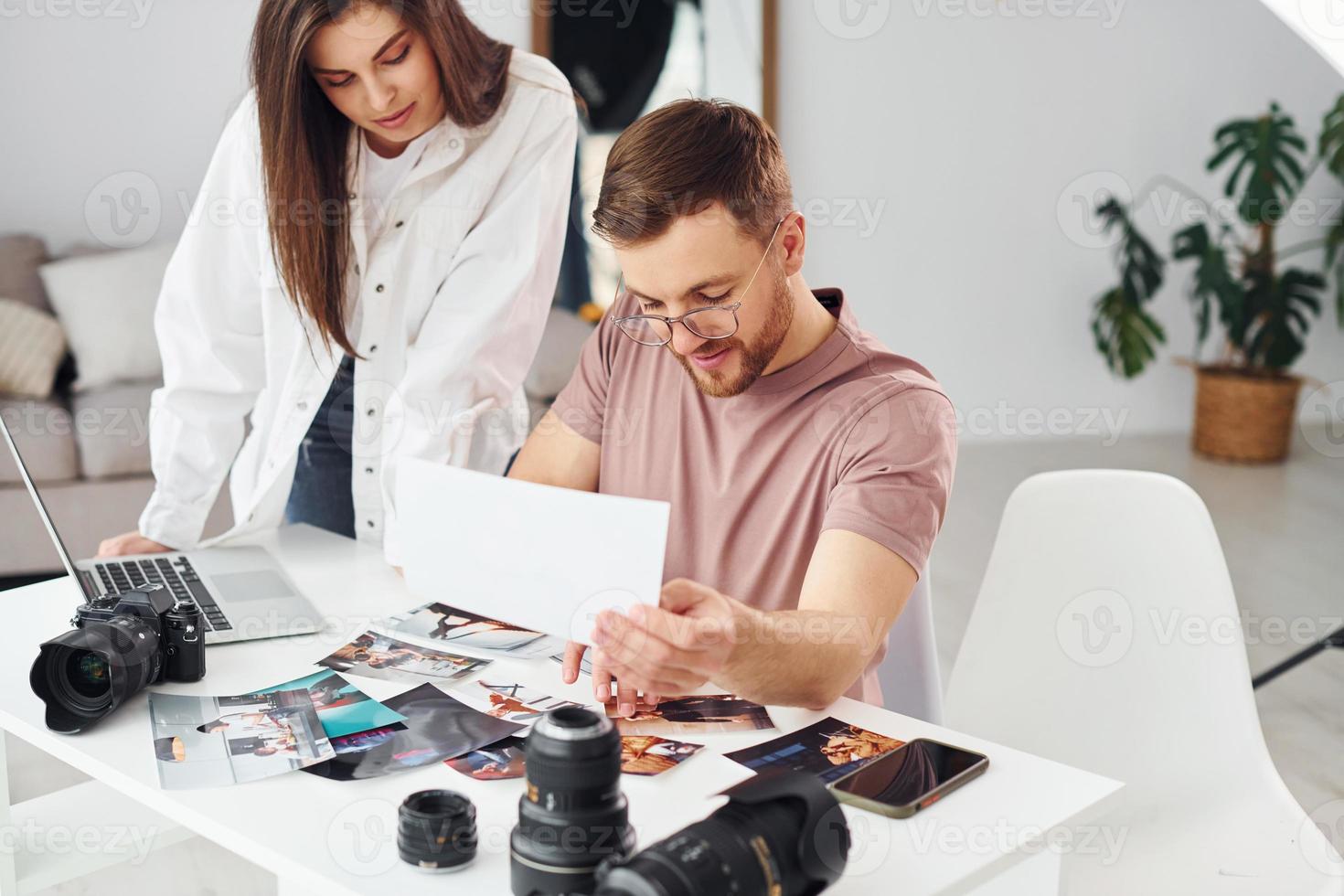 två fotografer i tillfällig kläder är arbetssätt inomhus på dagtid foto