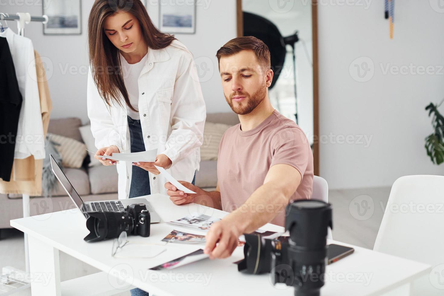 två fotografer i tillfällig kläder är arbetssätt inomhus på dagtid foto