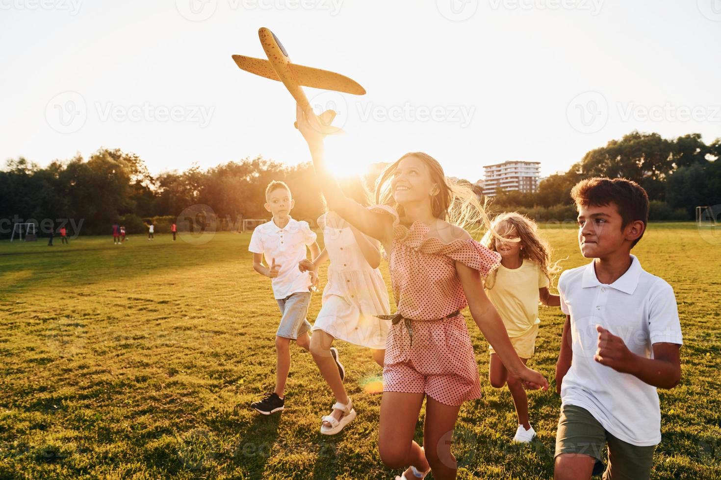 spelar med leksak plan. grupp av Lycklig barn är utomhus på de sportigt fält på dagtid foto