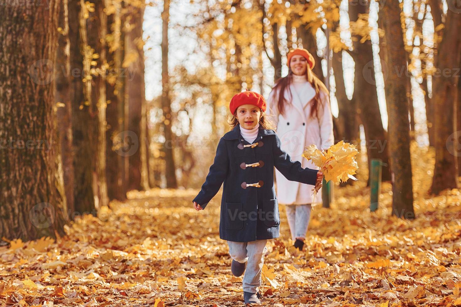 löpning och har roligt. mor med henne liten dotter är har promenad i de höst parkera foto