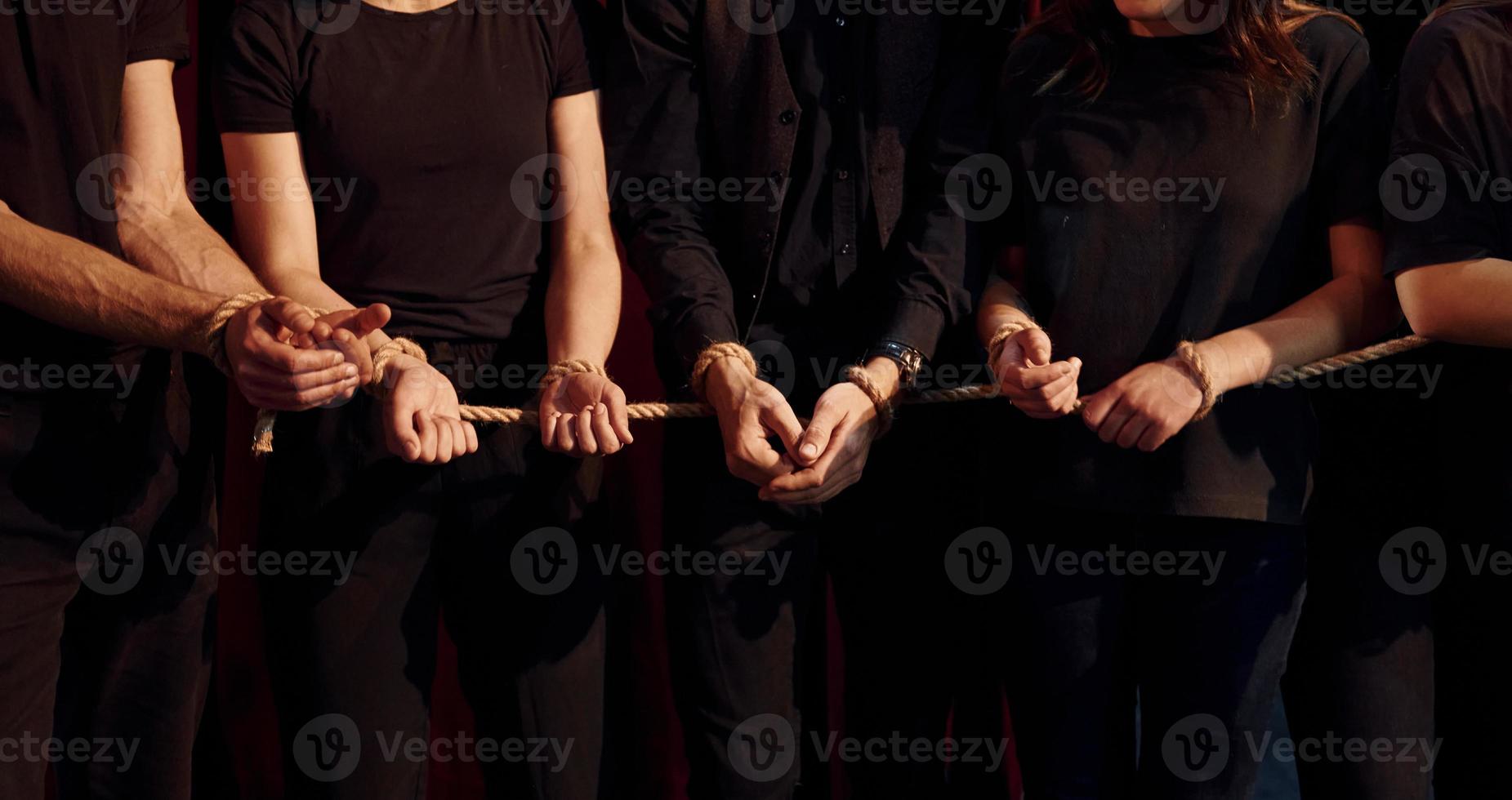 med rep i händer. grupp av aktörer i mörk färgad kläder på repetition i de teater foto