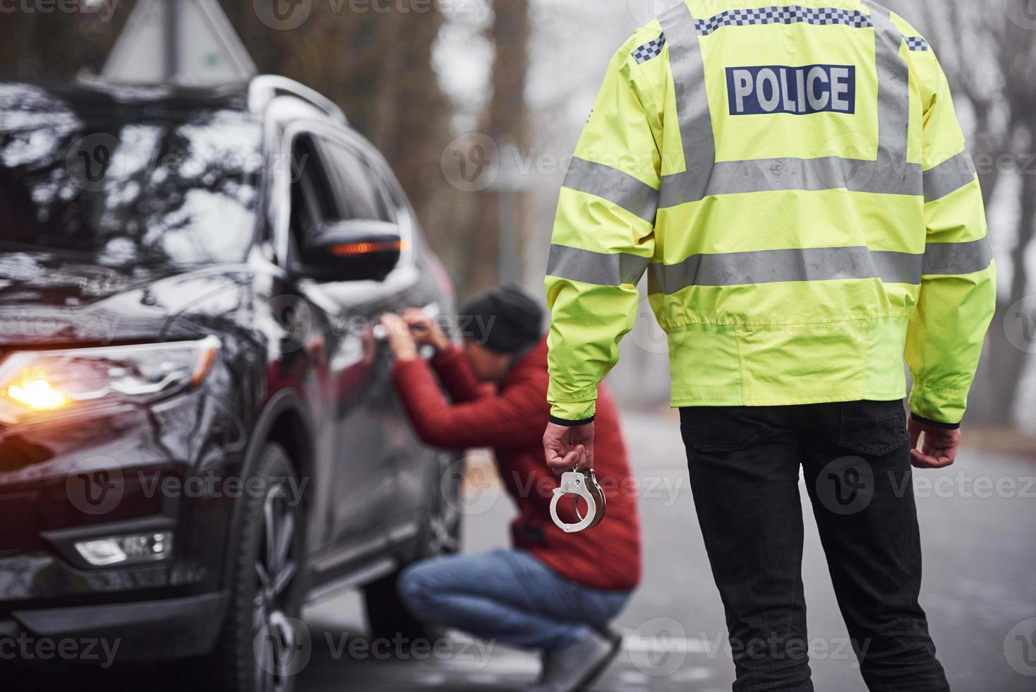 polis officer i grön enhetlig fångad bil stöld på de väg foto