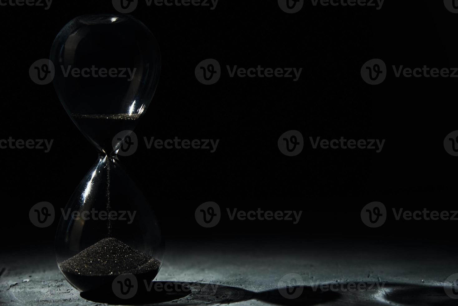 timglas på mörk bakgrund, närbild. brådskande karaktär och löpning ut av tid begrepp foto