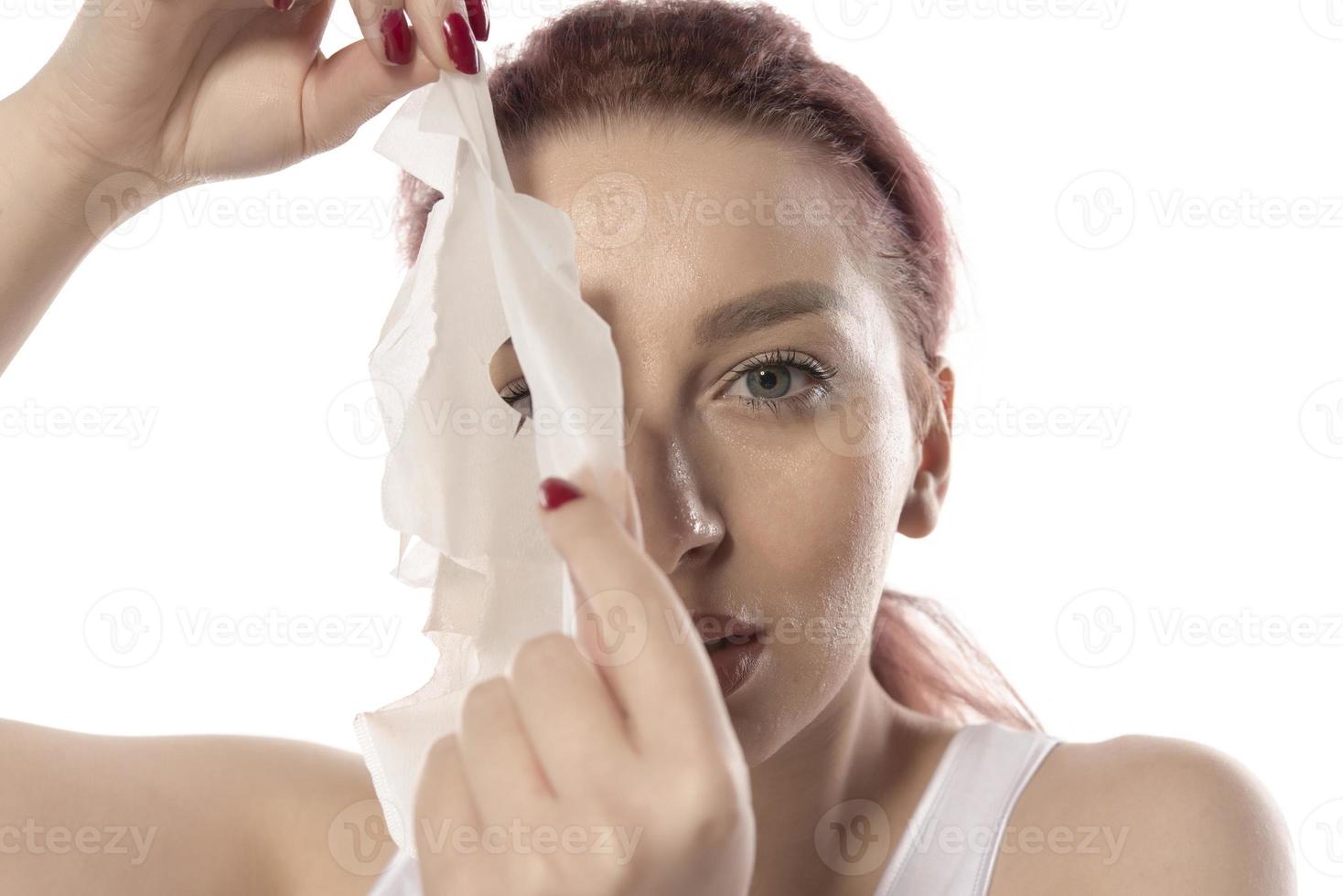 ansikte vård och skönhet behandlingar. kvinna med en ark fuktgivande mask på henne ansikte isolerat på vit bakgrund foto