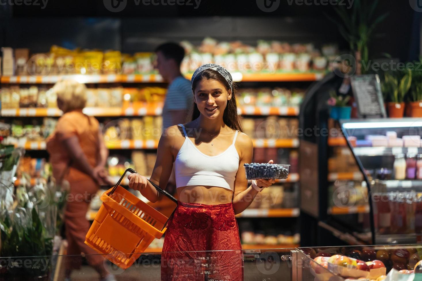 ung kvinna do handla i mataffär. välja blåbär i Lagra foto