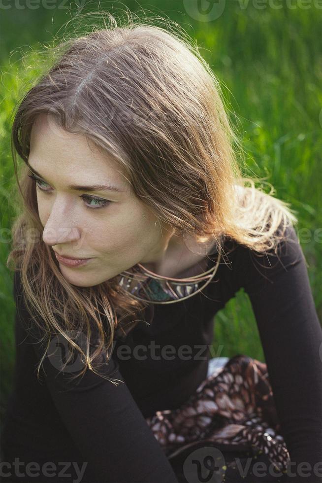 stänga upp kvinna ser bort och Sammanträde på gräs porträtt bild foto