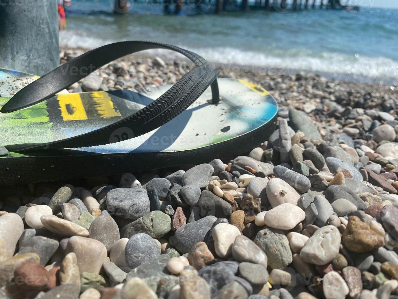 flip flops tofflor rörande hav vatten med skum från de vågor på de Strand av en sten strand foto