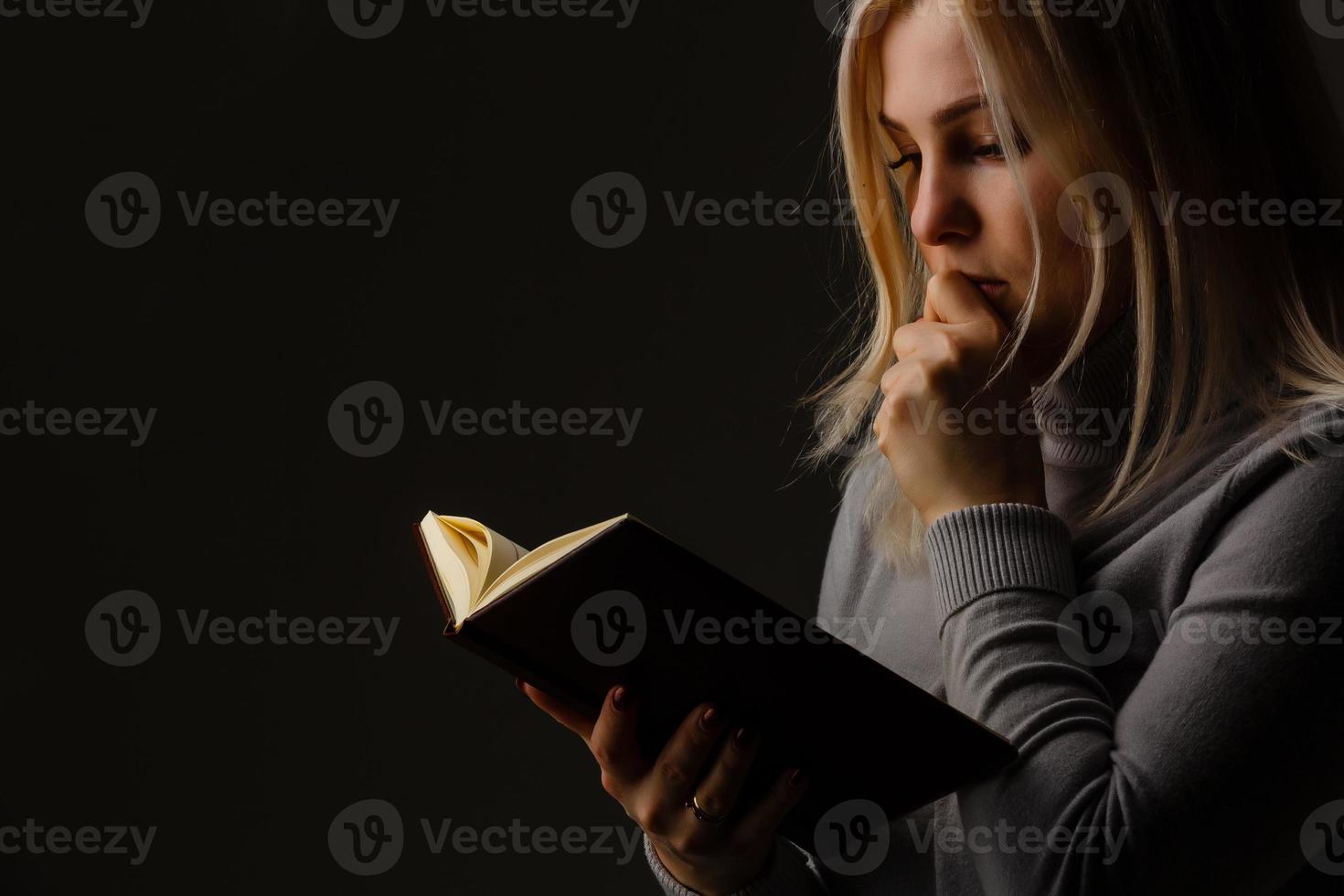en ung kvinna i bön under dramatisk ljus. foto