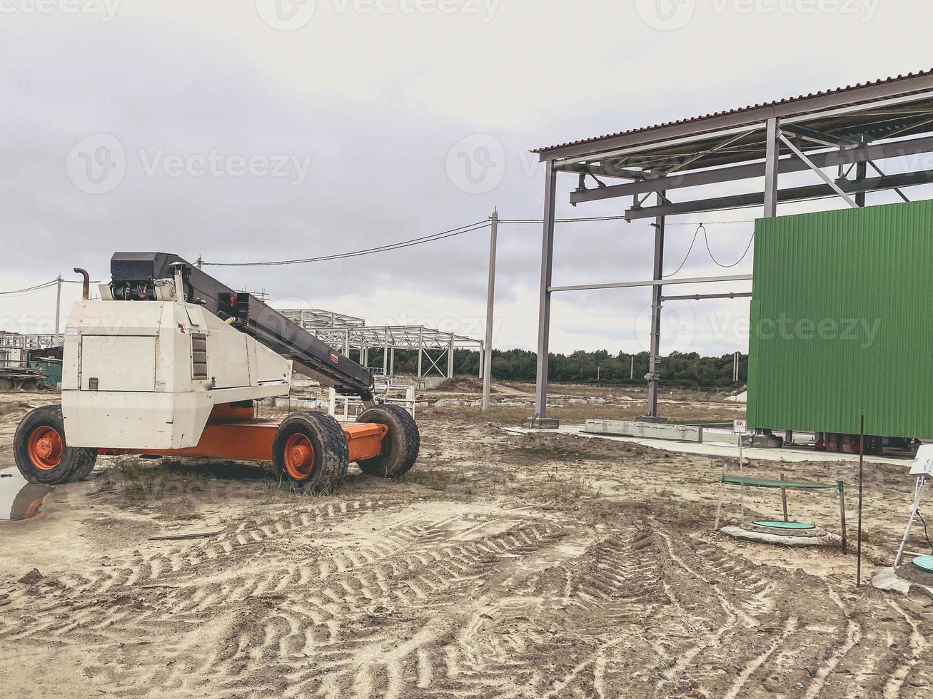 konstruktion webbplats av ett industriell komplex. maskin för transport tung byggnad material i orange. smuts på de jord, spår av tung maskineri foto