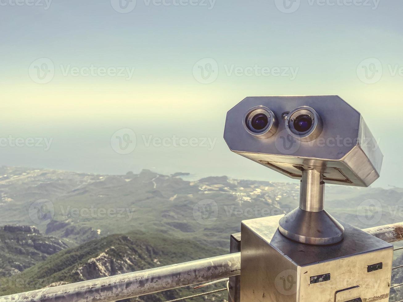 kikare på ett observation däck tillverkad av grå metall. sightseeing Turné, observera de se från de berg. kikare mot de bakgrund av en bergig enkel med grönska foto