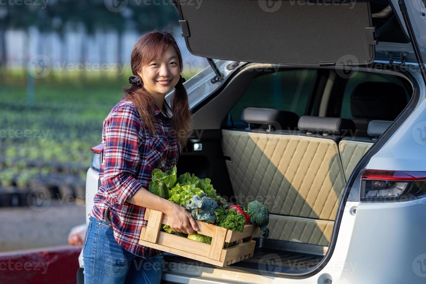 asiatisk jordbrukare är leverera nyligen skörda av organiska ämnen vegetabiliska låda in i de kund trunk bil för stödjande lokal- företag begrepp foto