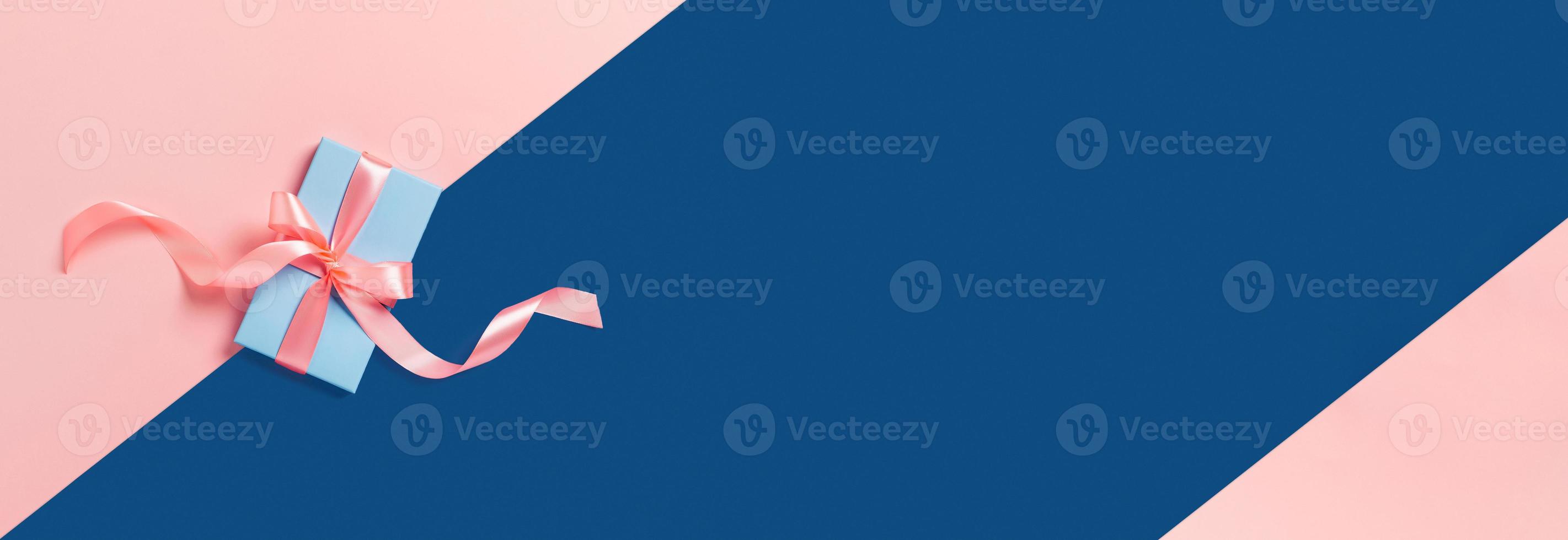 Semester webb-banner. blå låda med en rosa rosett på tvåtonad bakgrund. foto