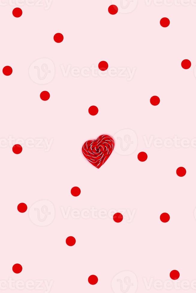 röd godis och konfetti på en rosa bakgrund. foto
