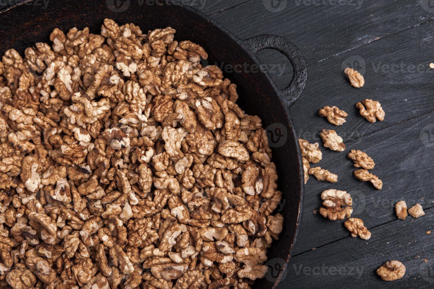 valnöt bakgrund. skalad valnötter på en järn tallrik på svart. valnötter en verklig super mat full av vitaminer och vegetabiliska fett foto