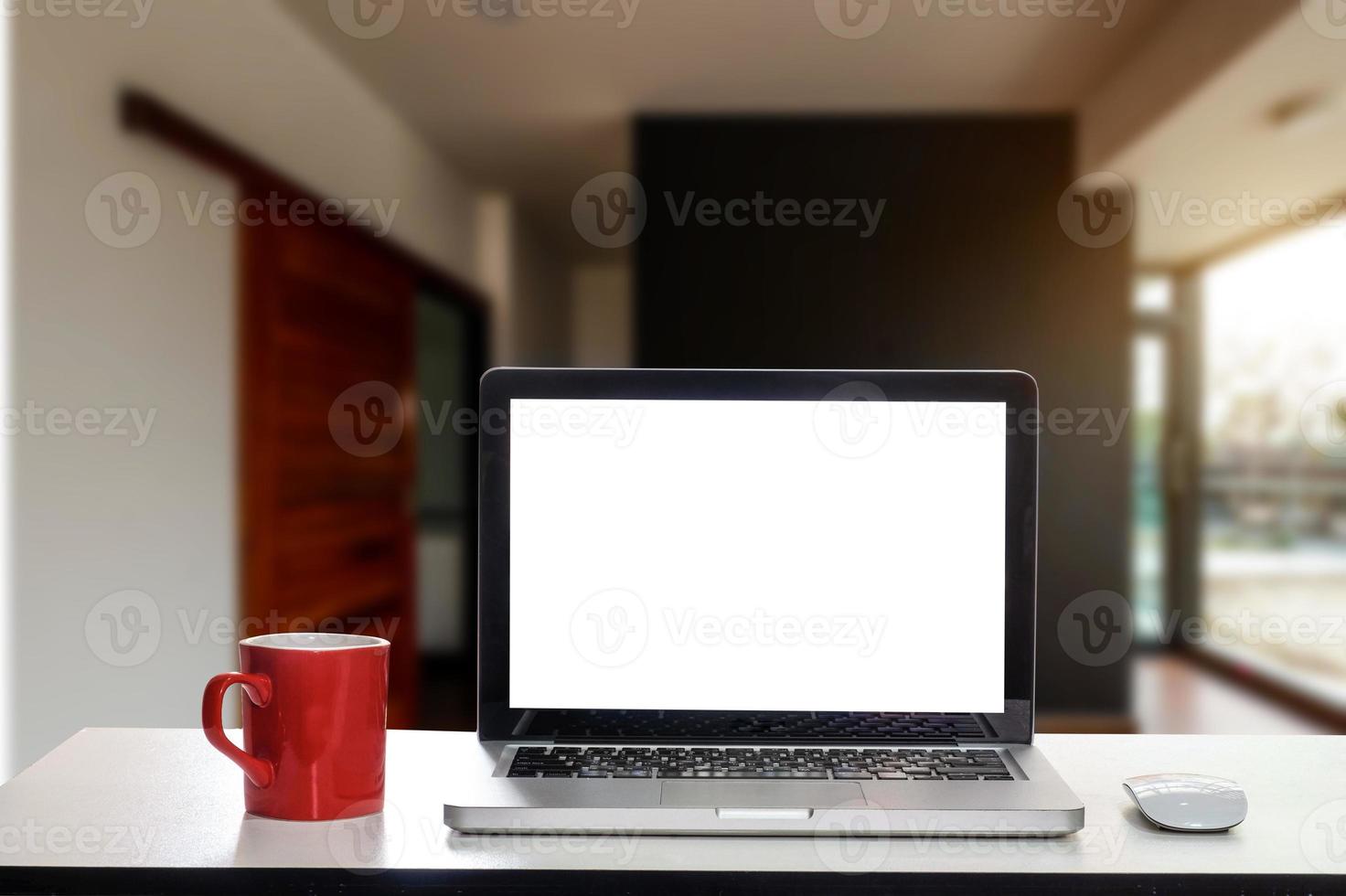 framifrån av kopp och bärbar dator, smartphone och surfplatta på bordet på kontoret foto